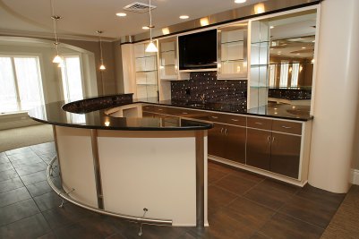 20-Lower level curved bar with stainless steel cabinets, glass shelving, and polished black granite countertops
