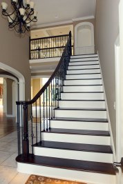 3-Curved stairway to second floor featuring stained maple treads, handrail, and newel posts, painted risers, and wrought iron railing.
